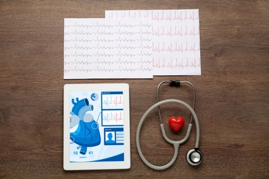 Flat lay composition with tablet and red heart on wooden table. Cardiology concept
