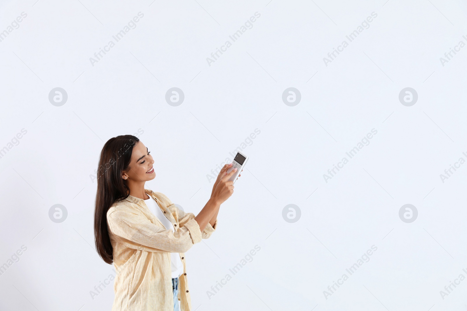 Photo of Young woman turning on air conditioner against white background