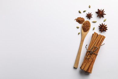 Photo of Cinnamon sticks, star anise and cardamom pods on white background, flat lay. Space for text