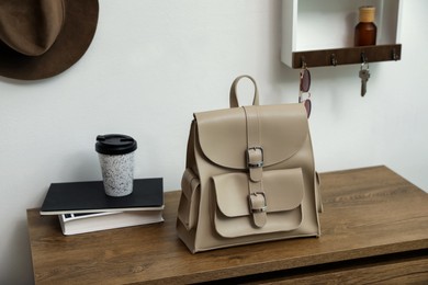 Photo of Stylish urban backpack on wooden chest of drawers in hallway