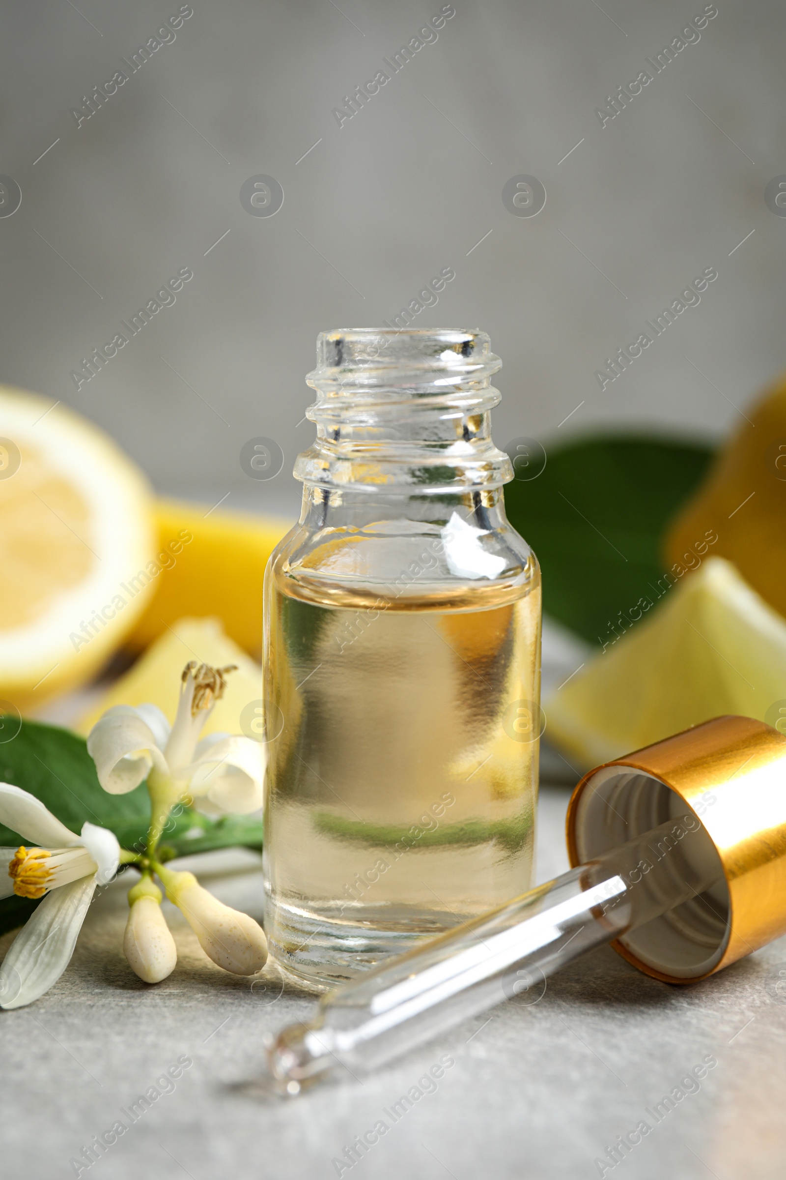 Photo of Citrus essential oil, flower and lemons on light table