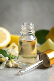 Photo of Citrus essential oil, flower and lemons on light table
