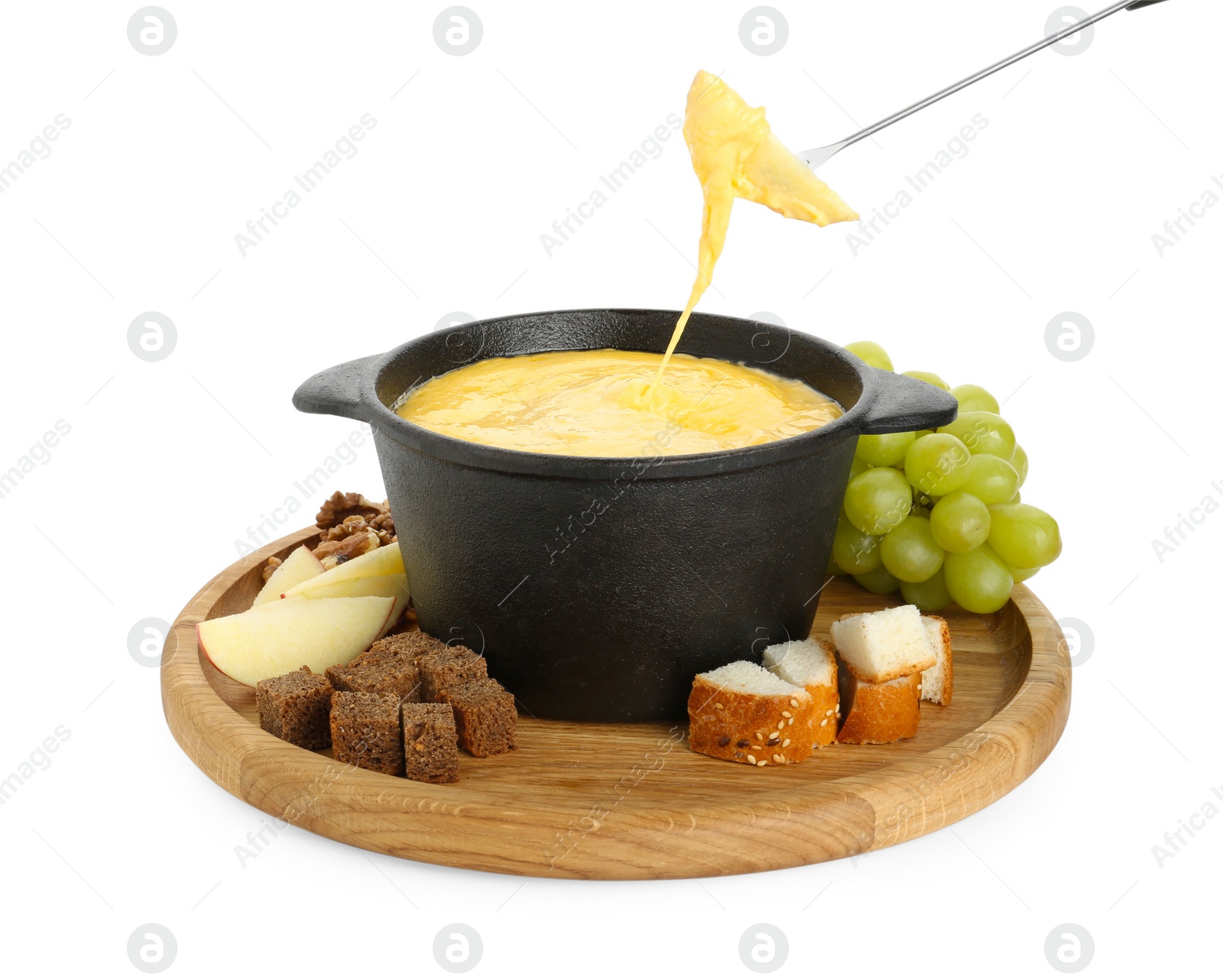 Photo of Dipping piece of apple into fondue pot with tasty melted cheese isolated on white