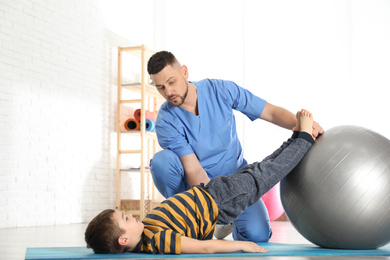 Orthopedist working with little boy in hospital gym