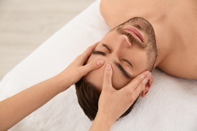 Handsome man receiving face massage in spa salon