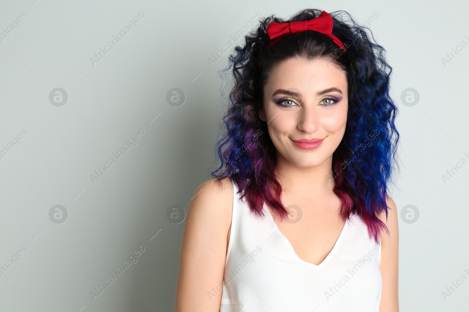 Photo of Young woman with bright dyed hair on light background