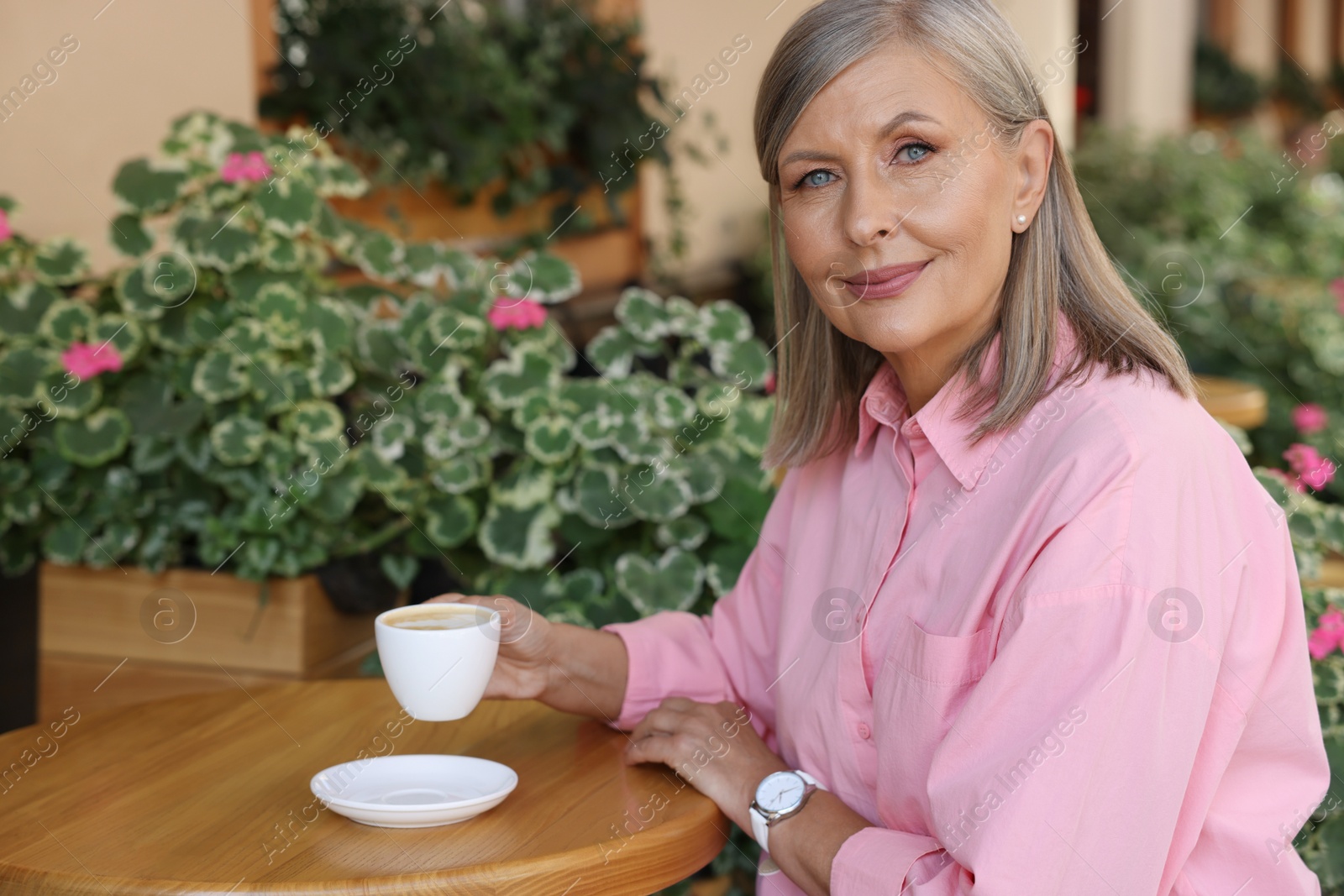 Photo of Portrait of beautiful senior woman drinking coffee at table in outdoor cafe