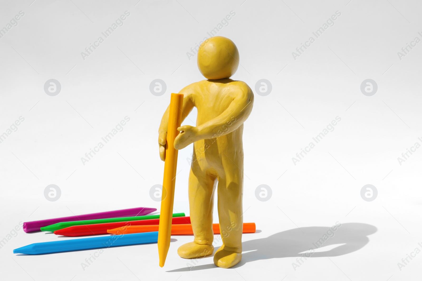 Photo of Human figure made of plasticine drawing with yellow pencil on white background