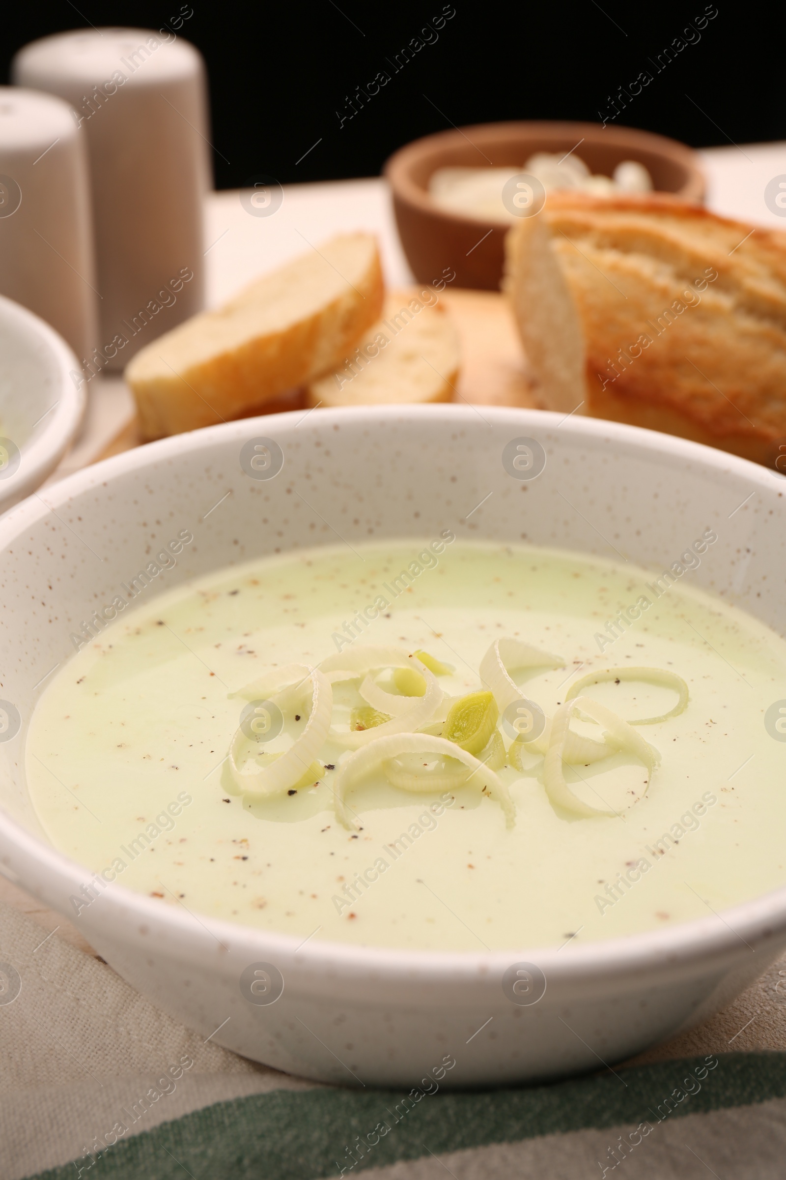 Photo of Bowl of tasty leek soup on table, closeup