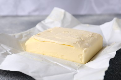 Photo of Piece of tasty homemade butter on paper wrap, closeup