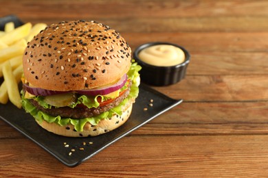 Photo of Burger with delicious patty, french fries and sauce on wooden table, closeup