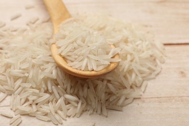 Photo of Raw basmati rice and spoon on white wooden table, closeup