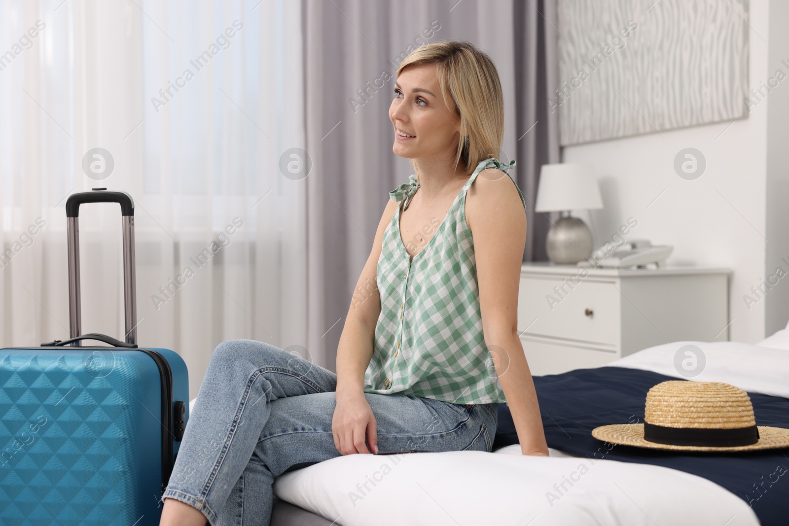 Photo of Smiling guest relaxing on bed in stylish hotel room