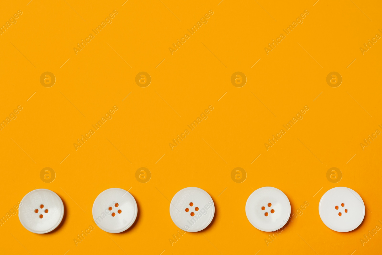 Photo of Line of white buttons on orange background, flat lay. Space for text