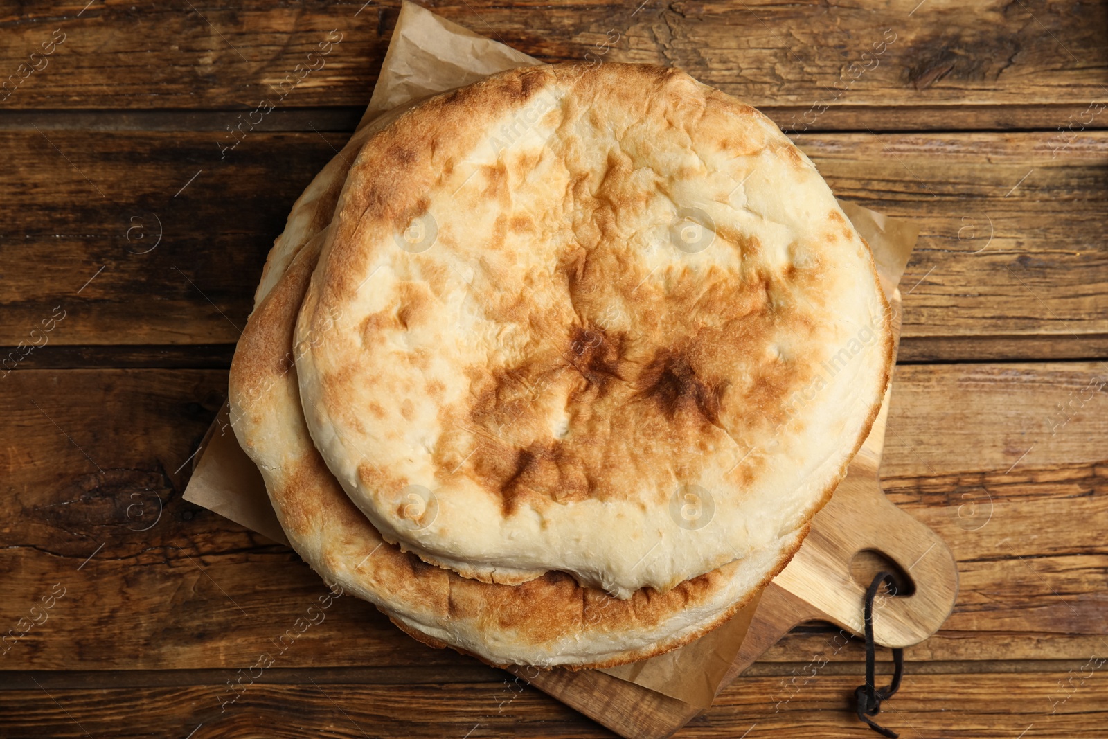 Photo of Loaves of delicious homemade pita bread on wooden table, top view