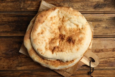 Photo of Loaves of delicious homemade pita bread on wooden table, top view