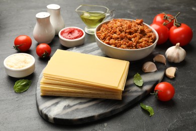 Photo of Products for cooking lasagna on dark textured table, closeup