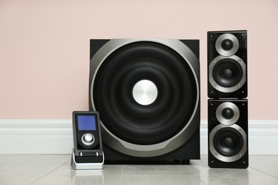 Modern powerful audio speaker system on floor near pink wall