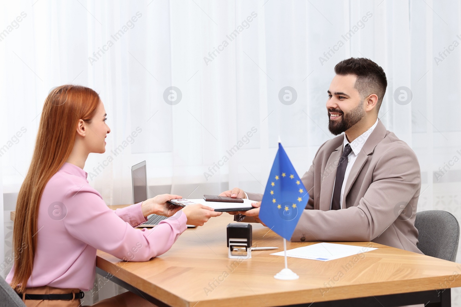 Photo of Immigration to European Union. Woman giving visa application form to embassy worker in office