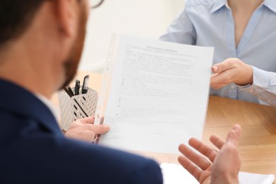Businesspeople working with documents at wooden table in office, closeup