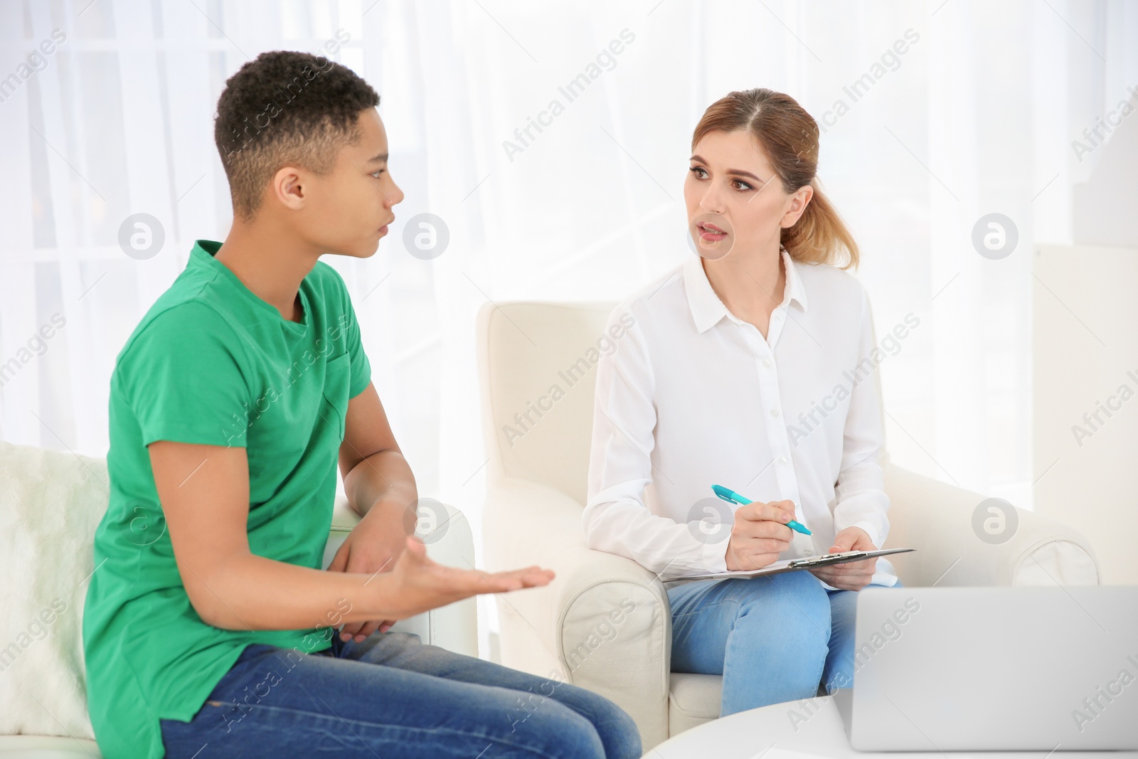 Photo of Female psychologist working with African American teenage boy in office