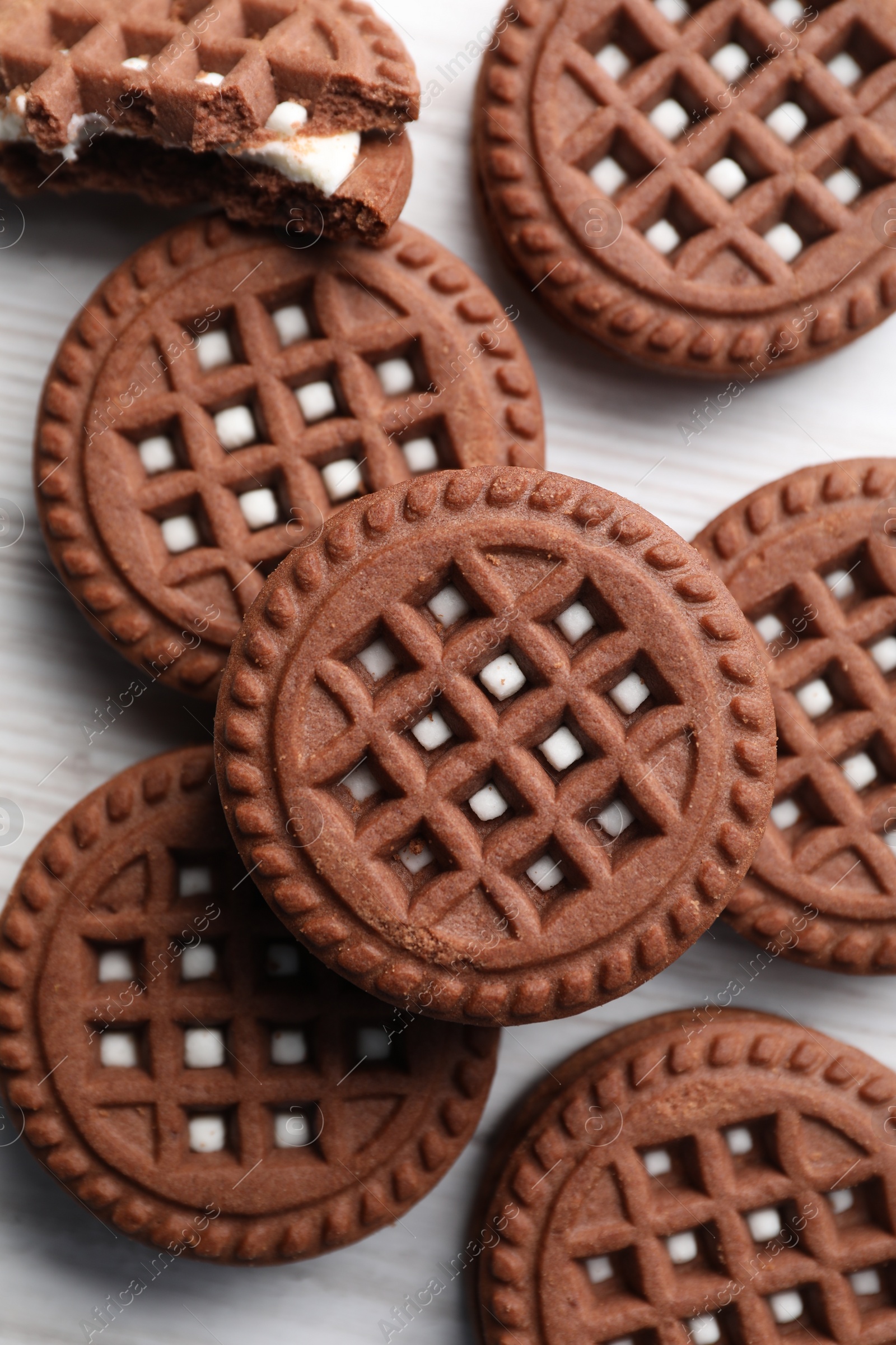 Photo of Tasty chocolate sandwich cookies with cream on white wooden table, flat lay