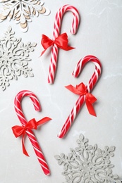 Photo of Sweet Christmas candy canes and snowflakes on grey background, flat lay