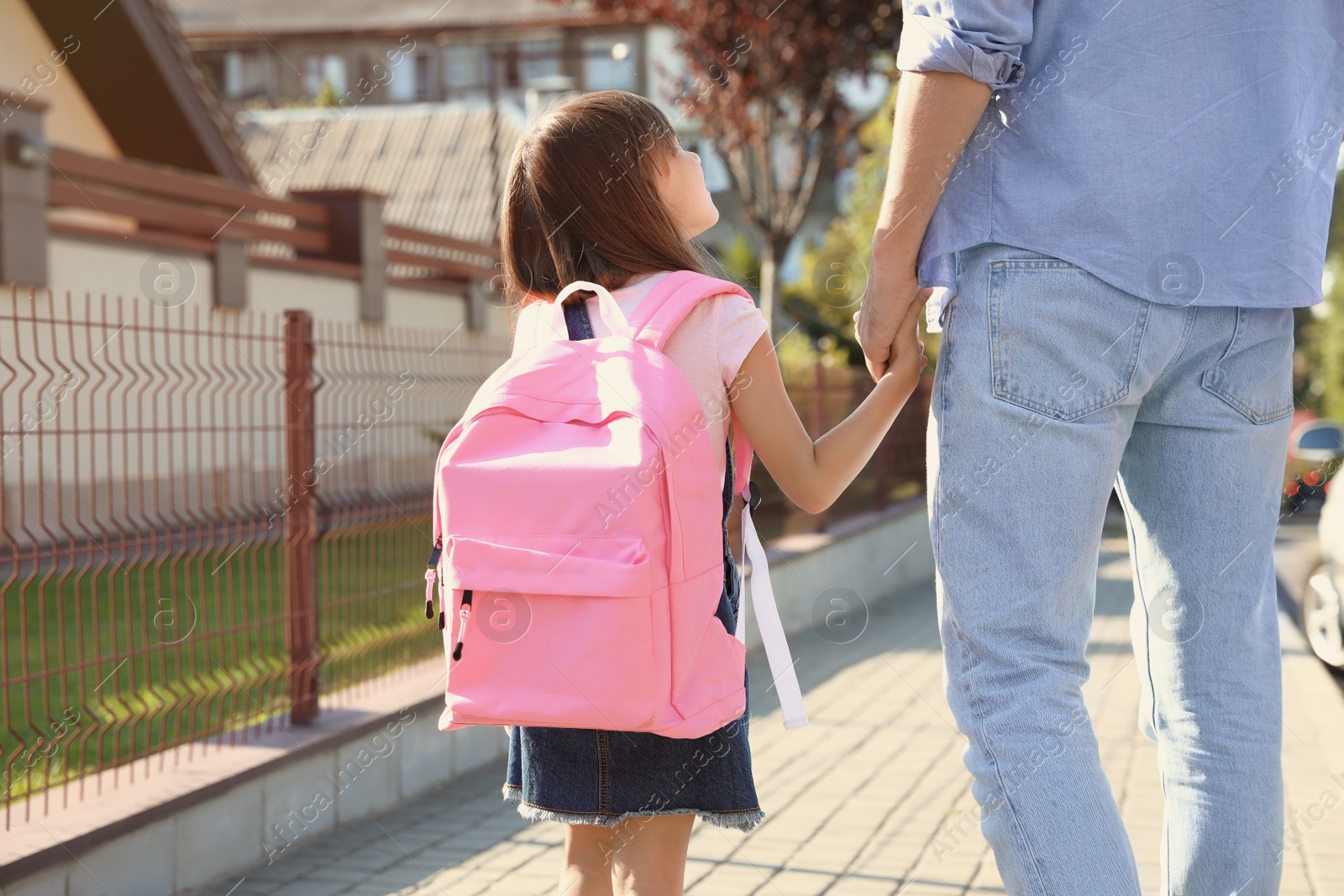 Photo of Father taking his little child to school on street