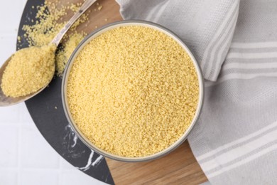 Photo of Bowl and spoon with raw couscous on table, flat lay