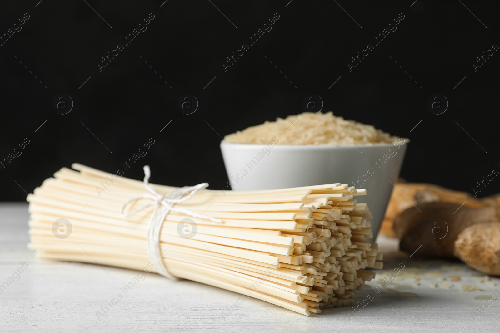 Photo of Raw rice noodles on white wooden table, closeup