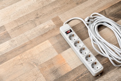 Photo of Extension cord on wooden floor, space for text. Electrician's equipment