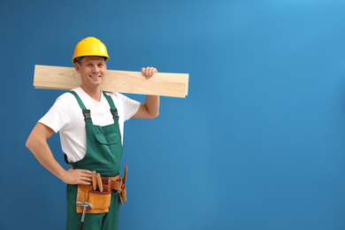 Photo of Handsome carpenter with wooden planks on blue background. Space for text