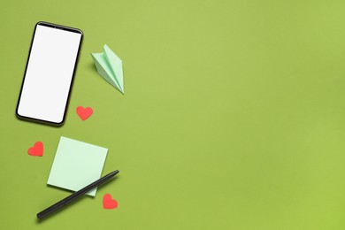 Photo of Long-distance relationship concept. Paper plane, empty note and hearts between smartphone and pen on light green background, flat lay with space for text