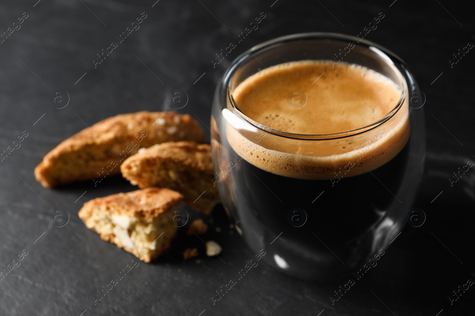 Photo of Tasty cantucci and cup of aromatic coffee on black table, closeup. Traditional Italian almond biscuits