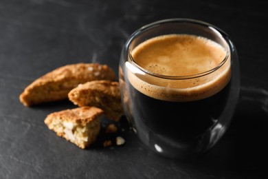 Tasty cantucci and cup of aromatic coffee on black table, closeup. Traditional Italian almond biscuits