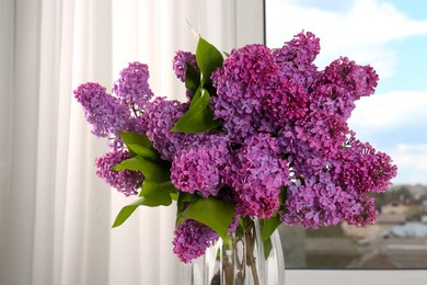 Photo of Beautiful lilac flowers in vase near window indoors