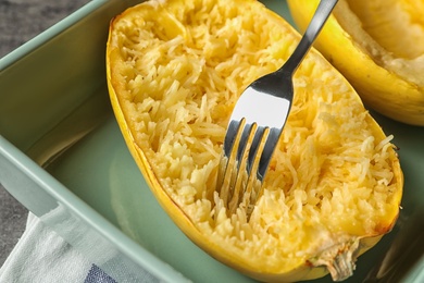 Photo of Scraping flesh of cooked spaghetti squash with fork on table