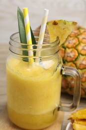 Photo of Tasty pineapple smoothie and fruit on table, closeup