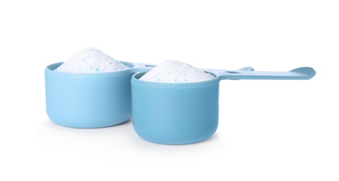 Laundry detergent in plastic measuring scoops on white background