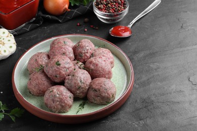Many fresh raw meatballs on black table, space for text