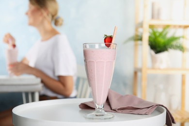 Photo of Tasty fresh milk shake with strawberry on table in cafe