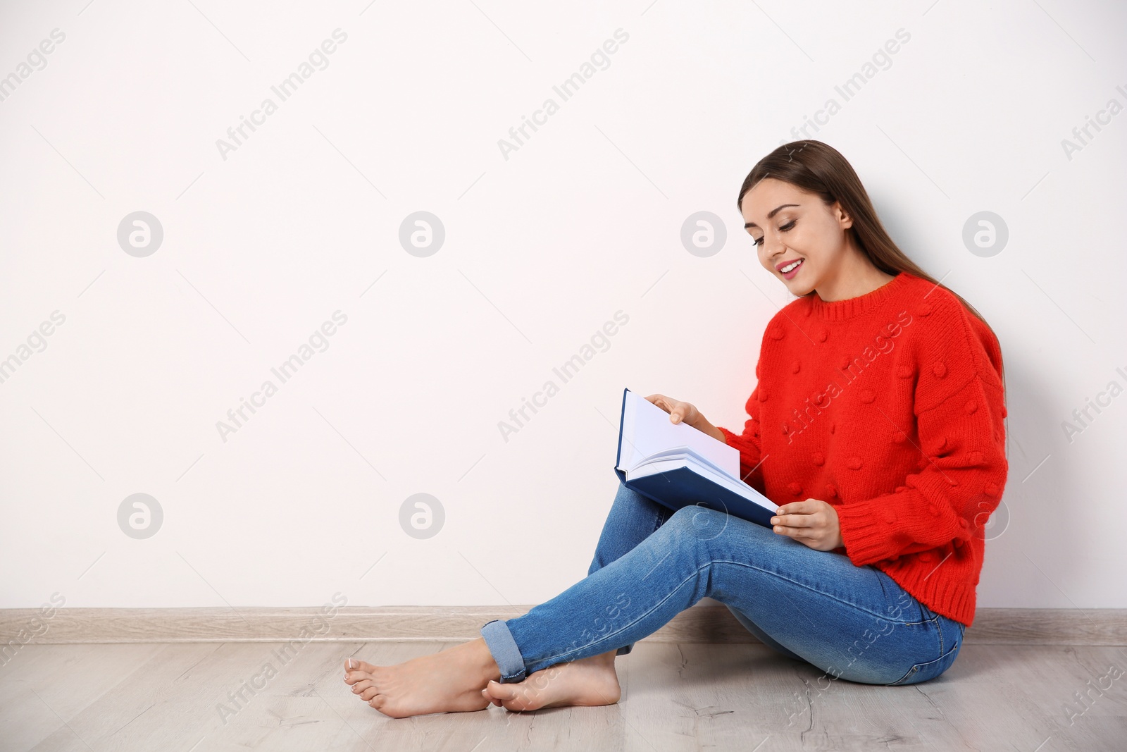 Photo of Young woman reading book on floor near wall, space for text