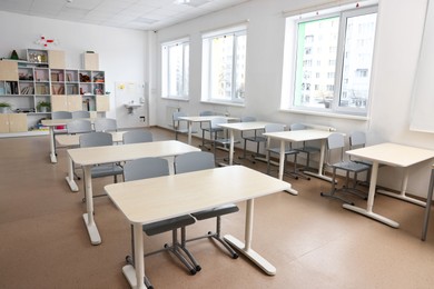 Empty school classroom with contemporary furniture and windows