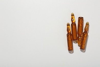 Glass ampoules with liquid on white background, top view. Space for text