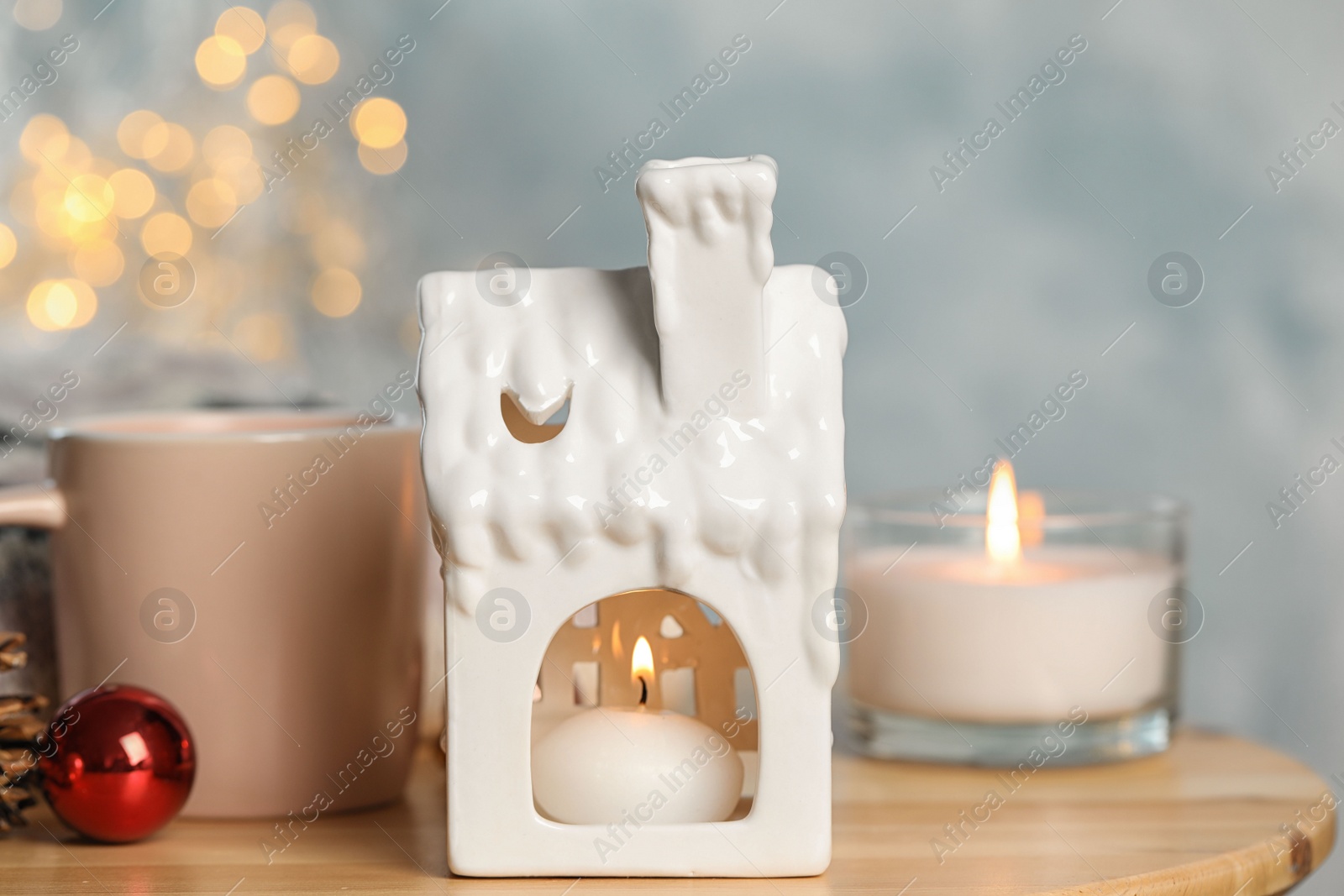 Photo of Composition with candle in house shaped holder on wooden table. Christmas decoration
