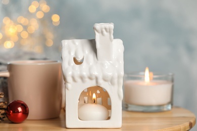 Photo of Composition with candle in house shaped holder on wooden table. Christmas decoration