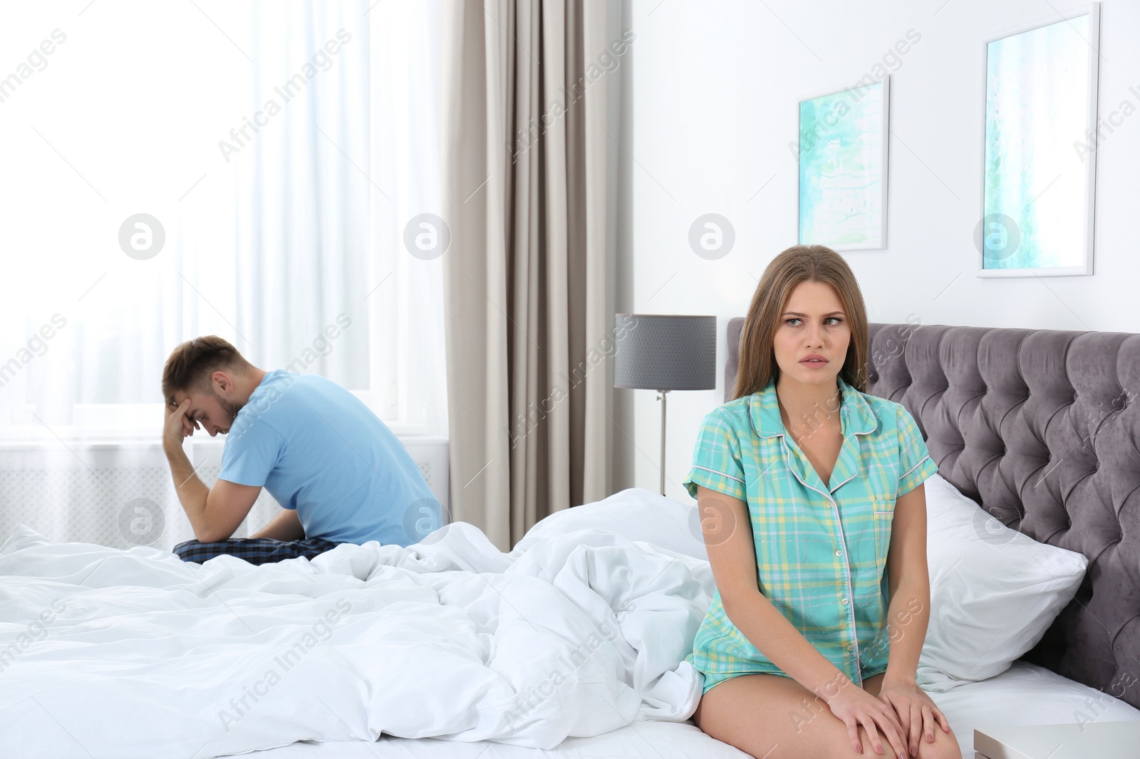 Photo of Young couple with relationship problems ignoring each other in bedroom