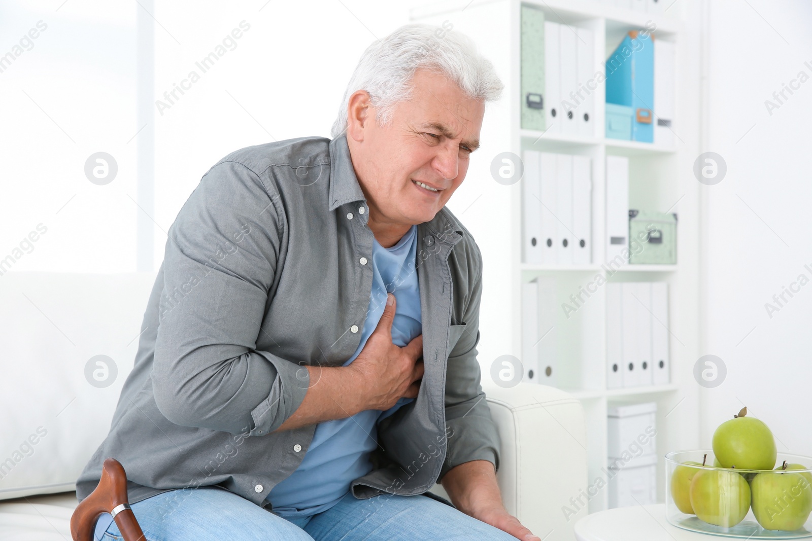 Photo of Senior man having heart attack on sofa