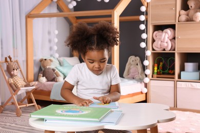 Photo of African American girl reading book at home