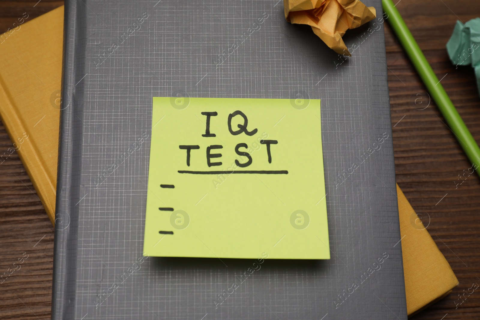 Photo of Sticky paper with words IQ Test, notebooks and pencil on wooden table, above view